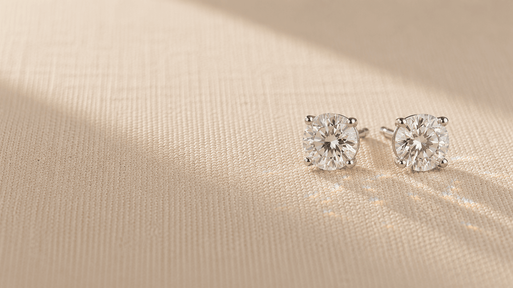 Diamond stud earrings on cream linen